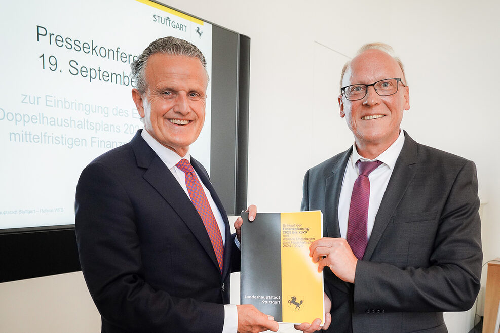 Oberbürgermeister Dr. Frank Nopper und Finanzbürgermeister Thomas Fuhrmann halten gemeinsam den gedruckten Entwurf des Doppelhaushalts 2024/2025